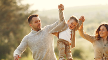 Family with cute little child. Father in a gray sweater. Sunset background.